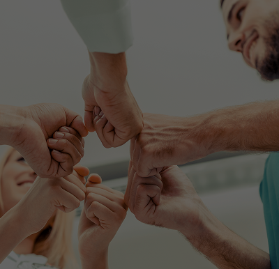 A group of people forming a circle, performing a collective fist bump.