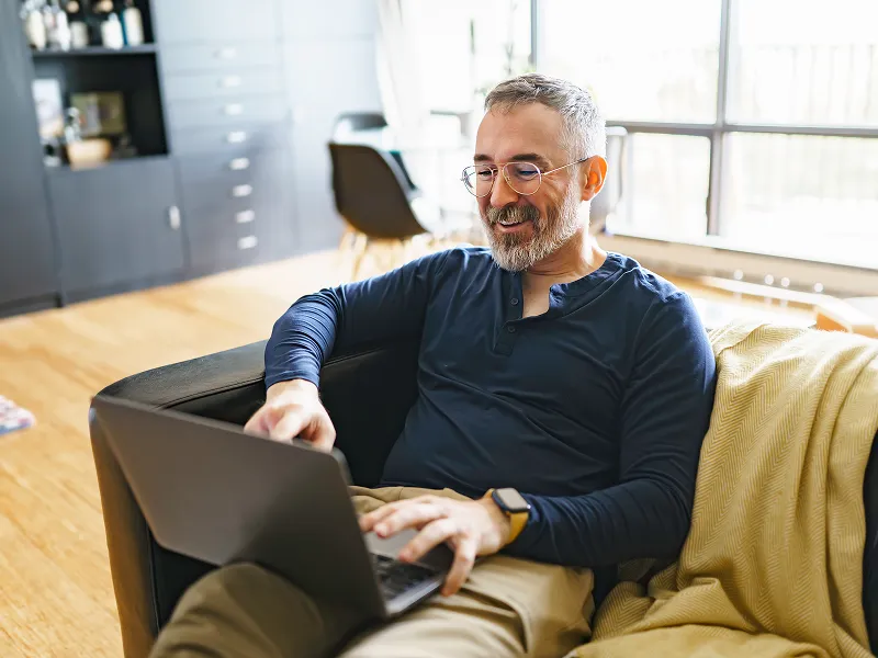 GettyImages-1352063893 A man sitting on the couch with his laptop
