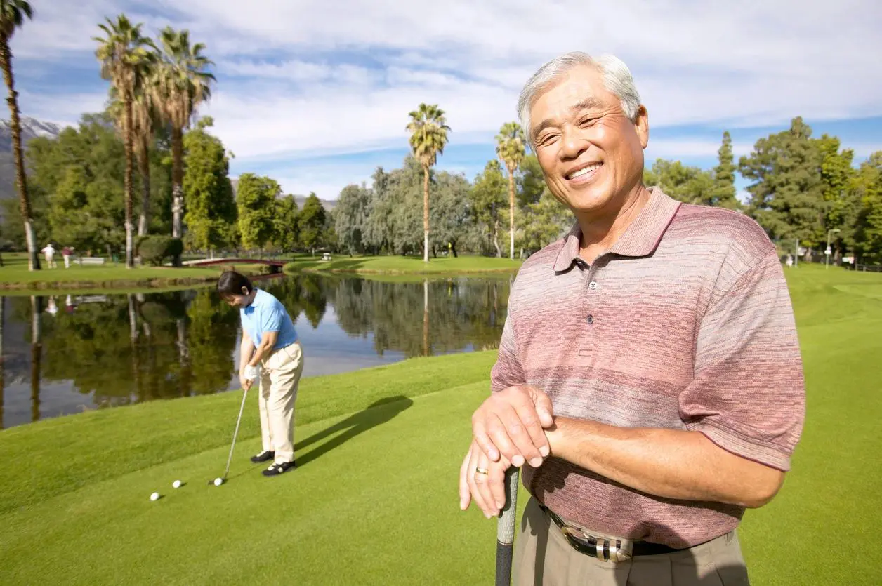 Two men playing golf on a green with trees in the background.